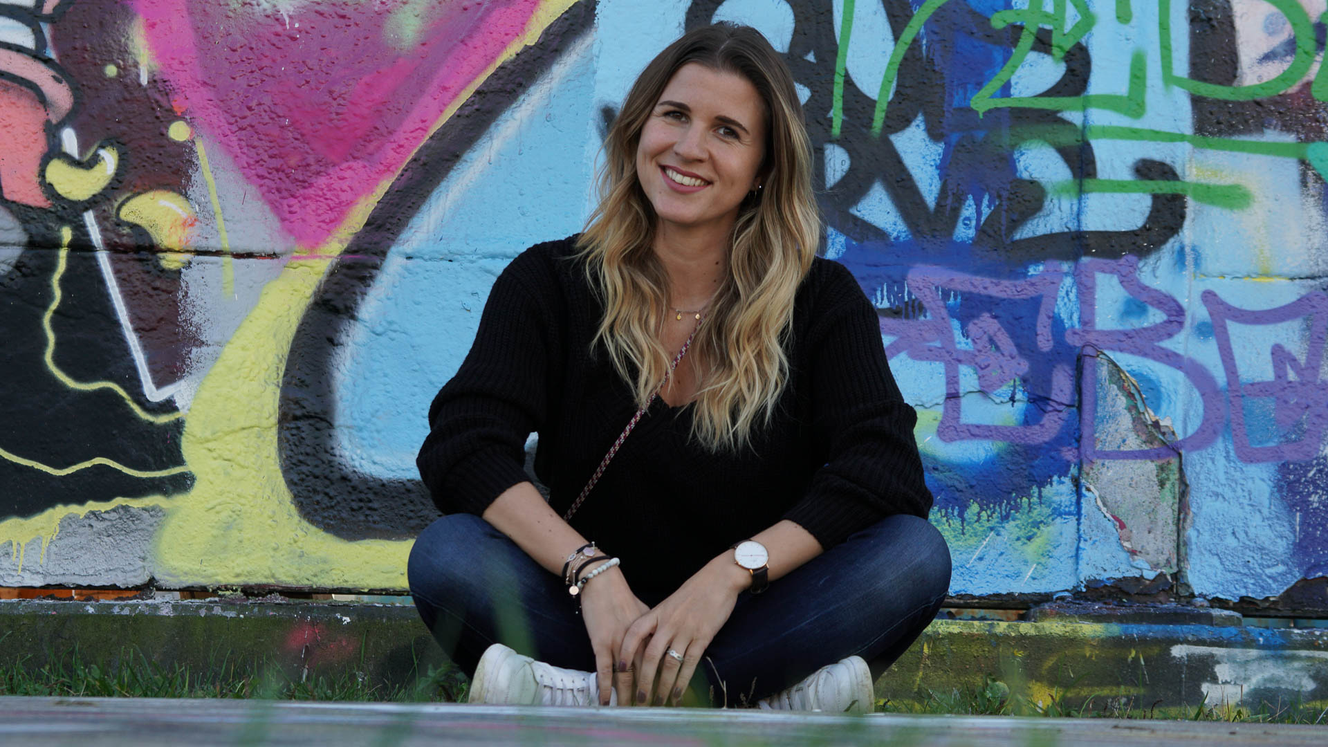 Kistina am sitzen vor Grafittiwand